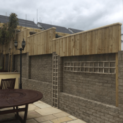 Brick wall that's been built up with feather edge fencing